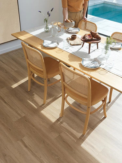 Summerhill Hybrid Plank Burlywood underfoot in a sunlit dining room with cane bentwood chairs and a poolside outlook